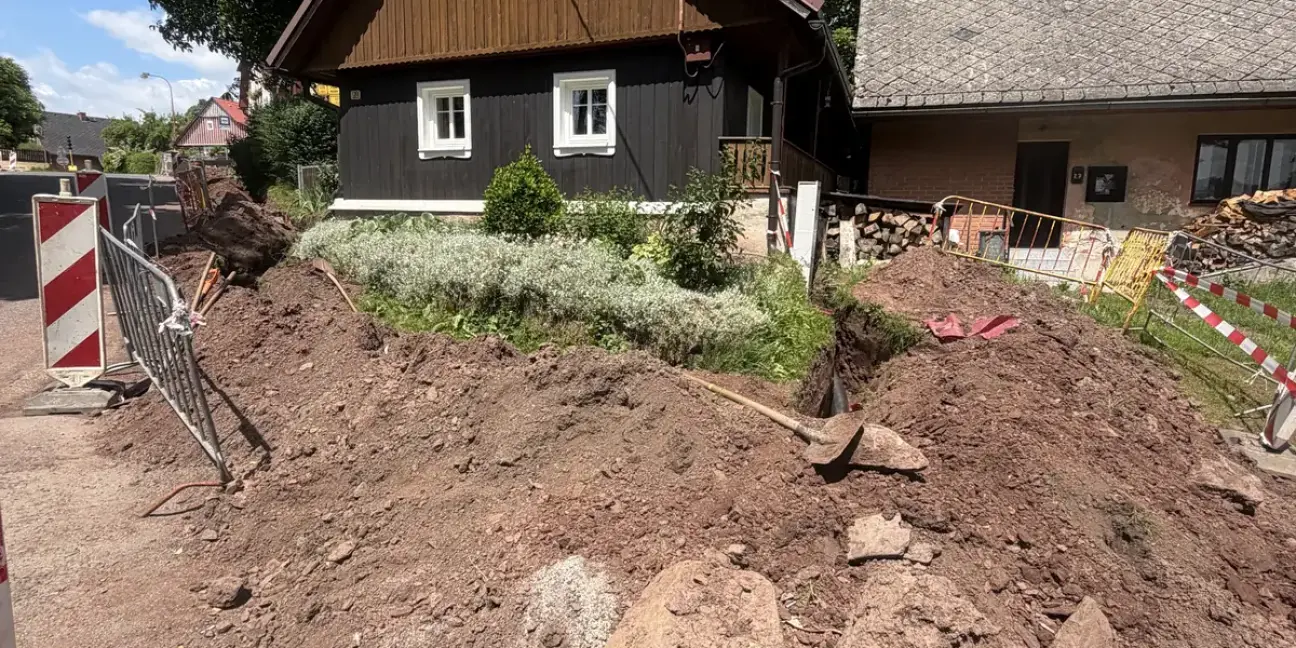Výkop pro kabelové vedení před roubenými domy v Benešově u Semil